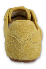 Rear view of a FILA Ritmo trainer in yellow suede, showcasing the textured, hairy suede heel counter with detailed tonal stitching and a glimpse of the inner tongue size label against a white background.
