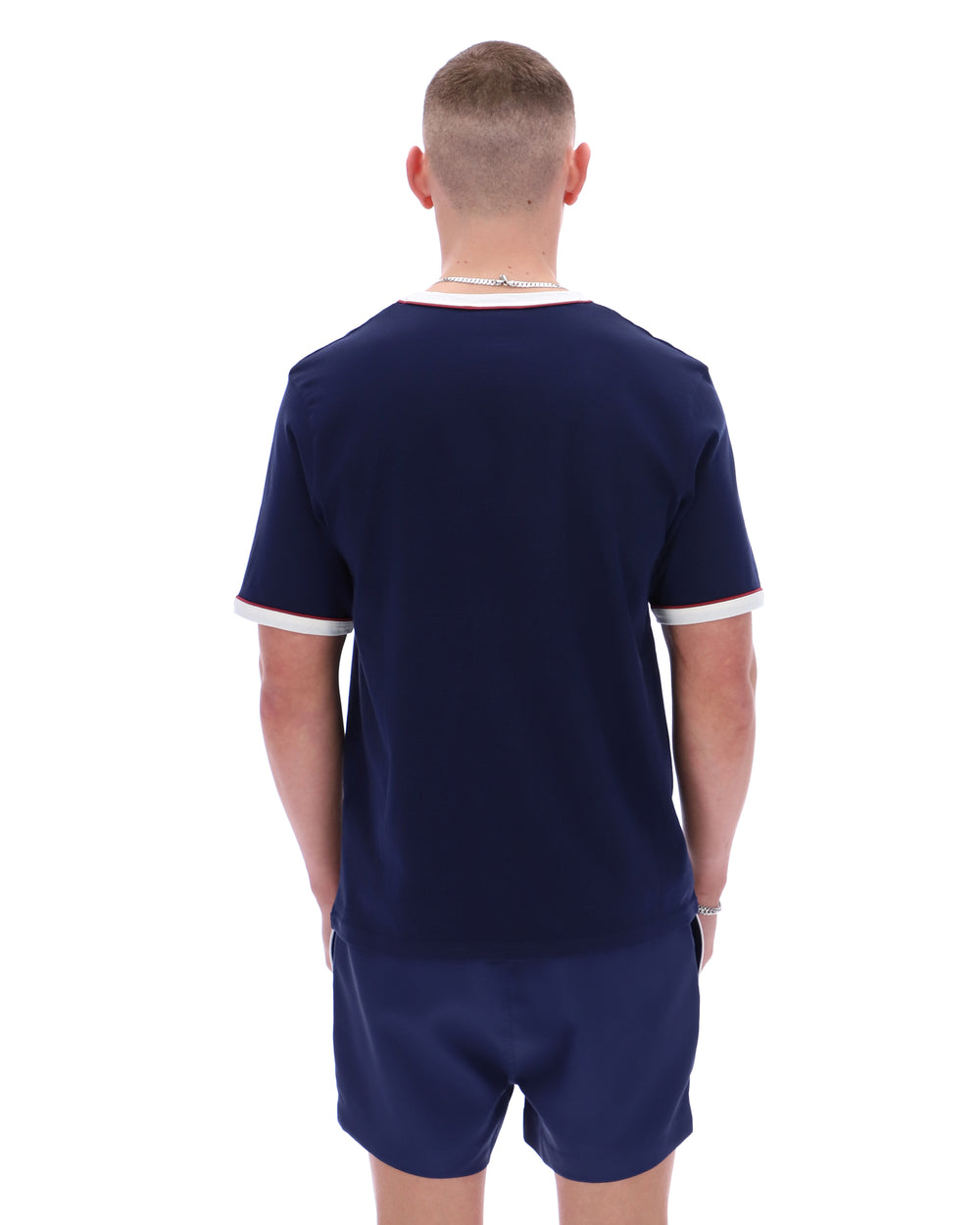 Man wearing a navy blue sports outfit with white trim on a white background