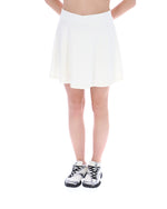 Person wearing a white skirt and black and white sneakers on a white background