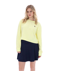 Woman wearing a light yellow sweater and navy skirt on a white background