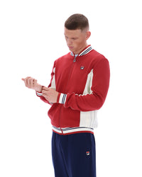 Man wearing a red and white tracksuit with a logo on a white background