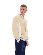 Man wearing a beige and navy varsity jacket on a white background