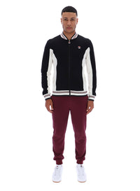 Person wearing a black and white tracksuit with maroon pants on a white background