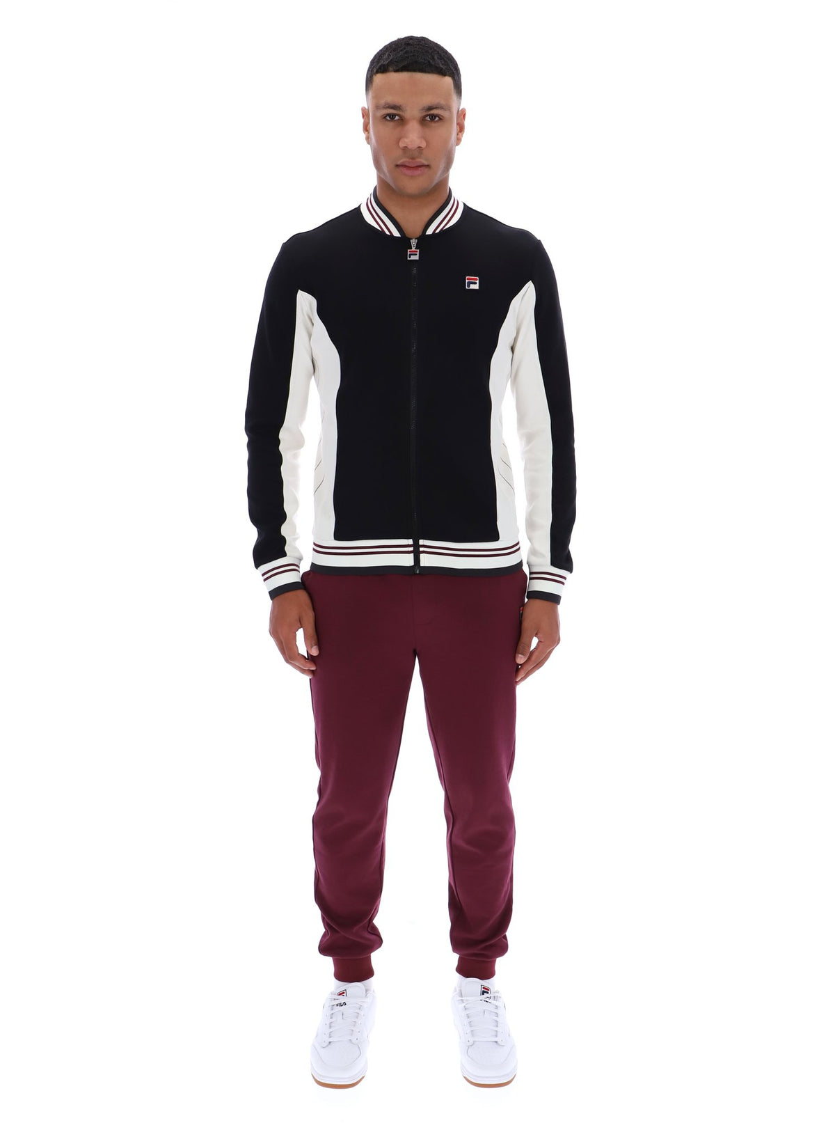 Person wearing a black and white tracksuit with maroon pants on a white background