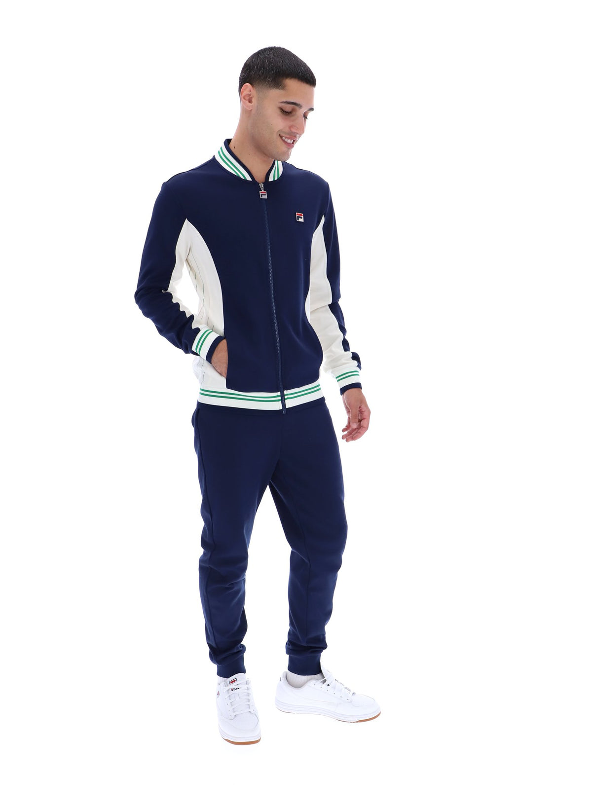Man wearing a navy and white track top with a FILA logo on the chest, paired with matching joggers, on a white background