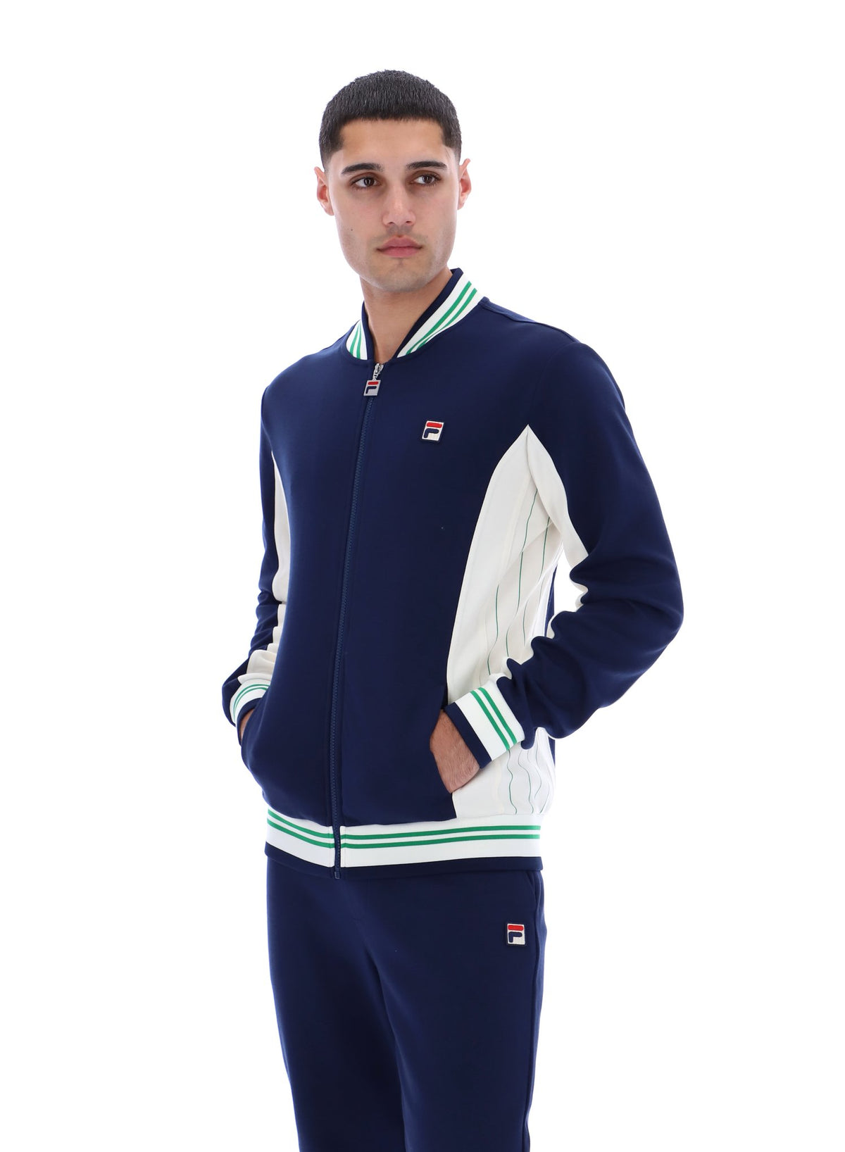 Man wearing a navy and white track top with a FILA logo on the chest, paired with matching joggers, on a white background