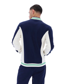 Man wearing a navy and white tracksuit with green accents on a white background