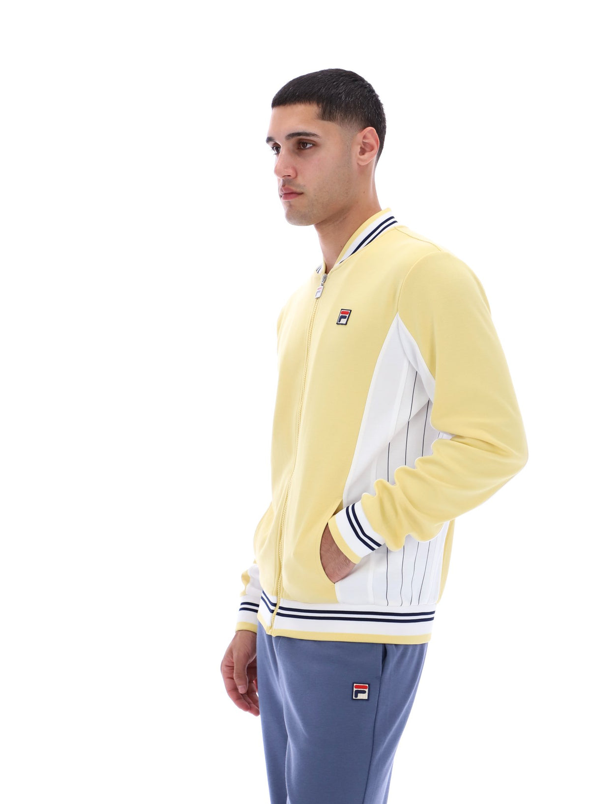 Man wearing a yellow tracksuit with a visible brand logo on a white background