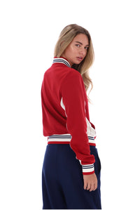 A woman modeling a red varsity-style jacket with white and navy striped ribbed trim, shown from a three-quarters back view against a plain white background.