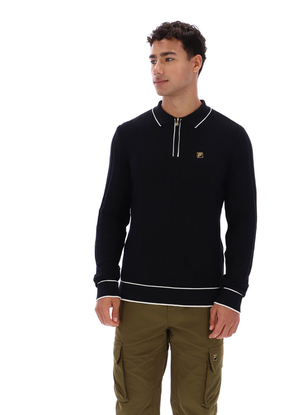 Man wearing a black sweater with white trim and a small FILA Gold logo on the chest, paired with green FILA cargo pants, against a white background