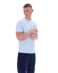 Man wearing a light blue t-shirt with a logo on a white background