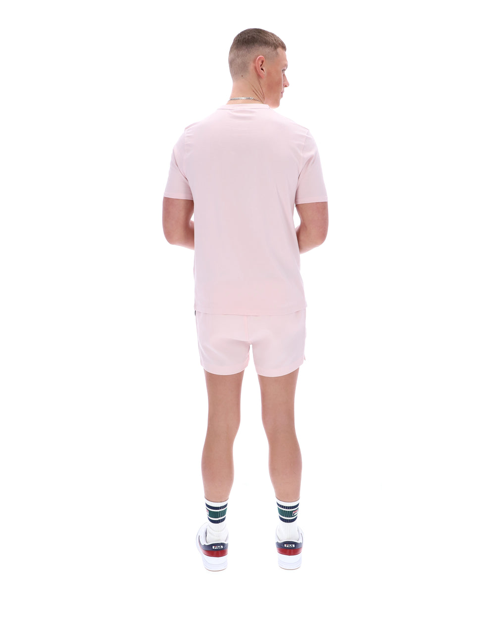 Person wearing a light pink outfit with white shoes on a white background