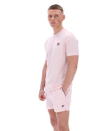 Man wearing a light pink sports outfit with a brand logo on a white background