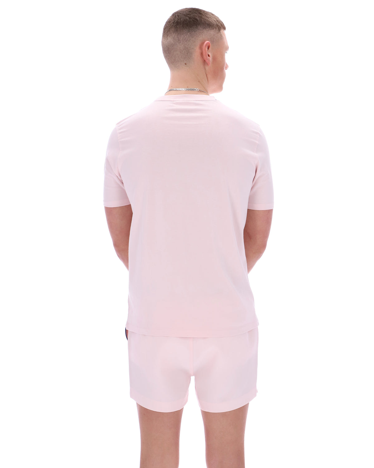 Person wearing a light pink t-shirt and shorts set on a white background