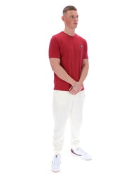 Man wearing a red t-shirt and white pants on a white background
