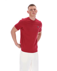 Man wearing a red t-shirt with a small logo on a white background