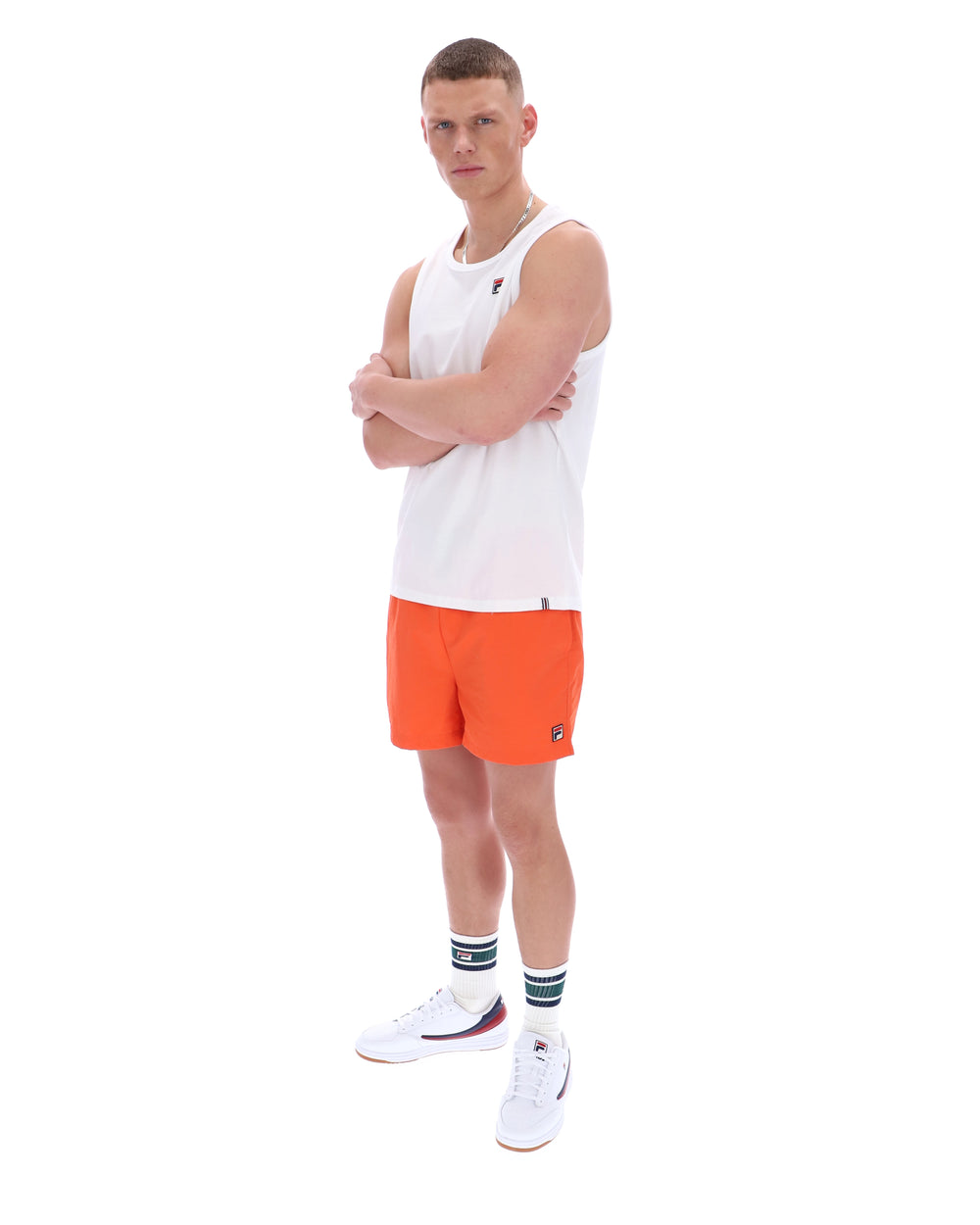 Man wearing a white tank top and orange shorts on a white background
