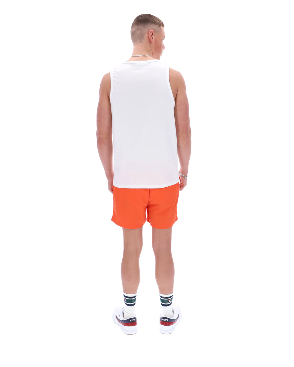 Man wearing a white tank top and orange shorts on a white background