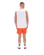 Man wearing a white tank top and orange shorts on a white background