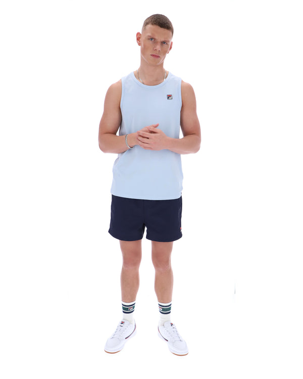 Man wearing a light blue sleeveless shirt and navy shorts on a white background