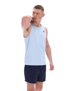 Man wearing a light blue sleeveless shirt and navy shorts on a white background