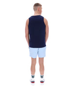 Man wearing a navy sleeveless shirt and light blue shorts on a white background