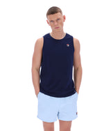Man wearing a navy sleeveless shirt with a logo and light blue shorts on a white background