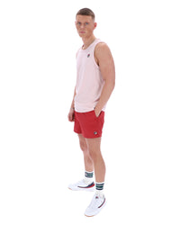 Man wearing a light pink sleeveless shirt and red shorts on a white background