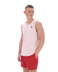 Man wearing a light pink sleeveless shirt and red shorts on a white background