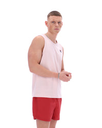 Man wearing a light pink sleeveless shirt and red shorts on a white background