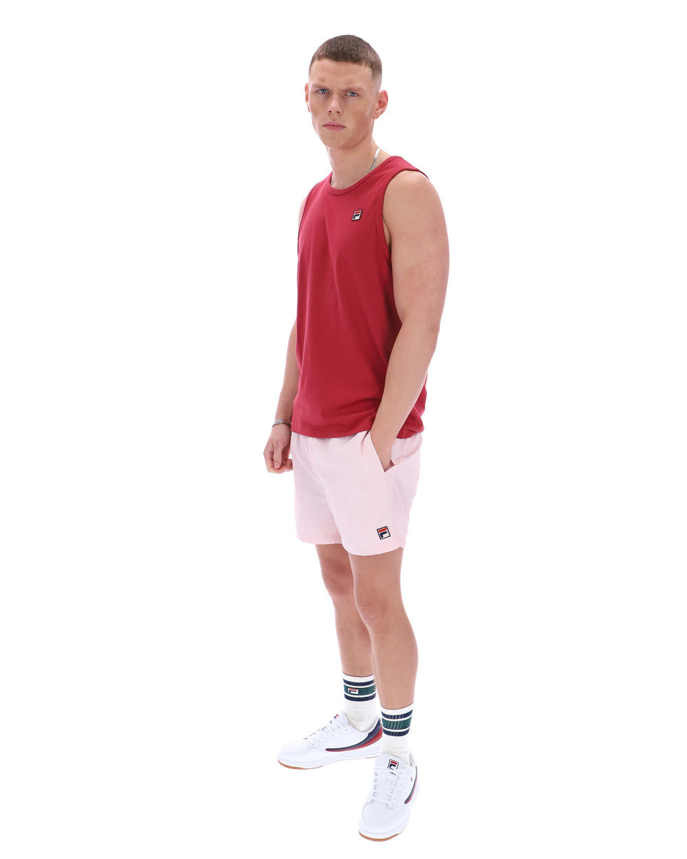 Man wearing a red sleeveless shirt and white shorts with a logo on a white background