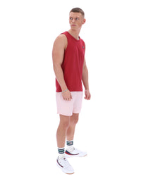 Man wearing a red sleeveless shirt and pink shorts on a white background