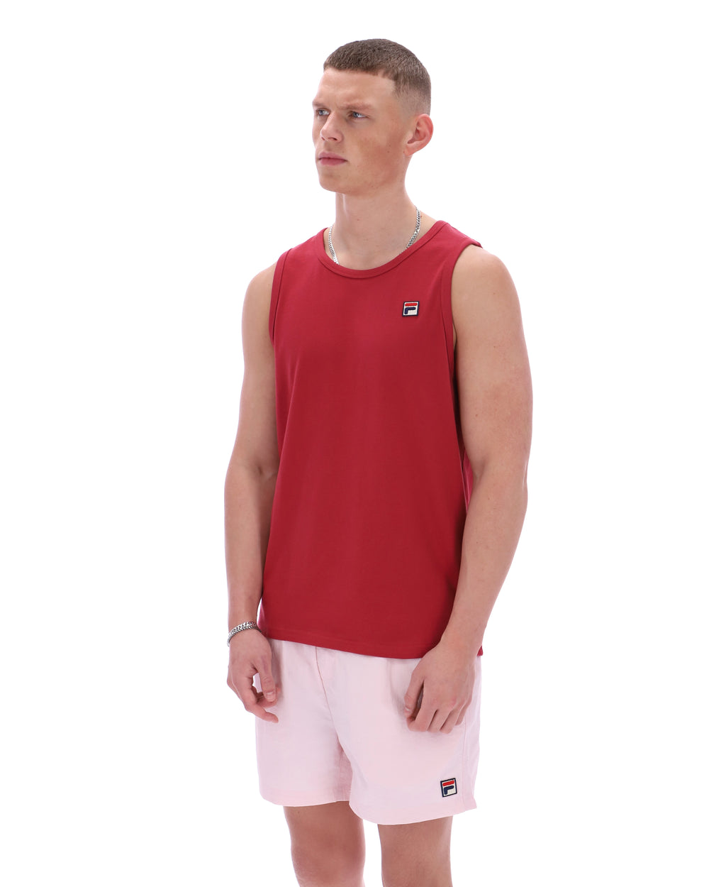 Man wearing a red sleeveless shirt and pink shorts on a white background