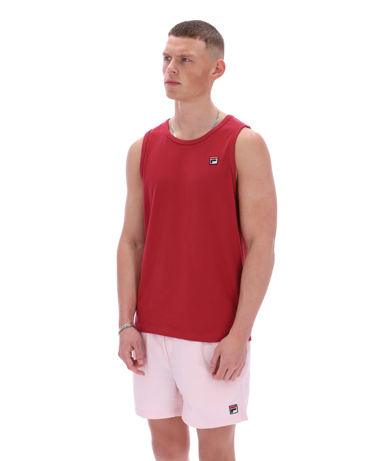 Man wearing a red sleeveless shirt and pink shorts on a white background