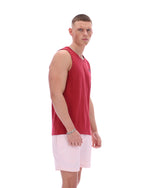 Man wearing a red sleeveless shirt and light pink shorts on a white background