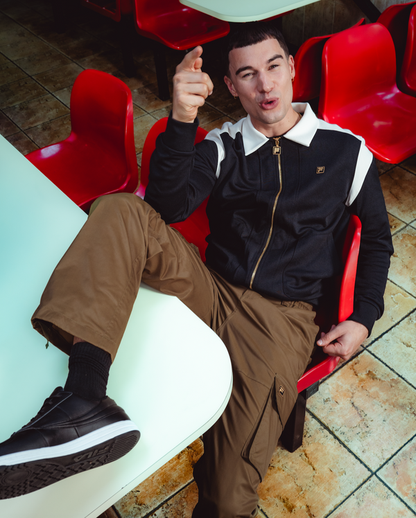 Man sitting on a red chair in a casual setting with a white table.