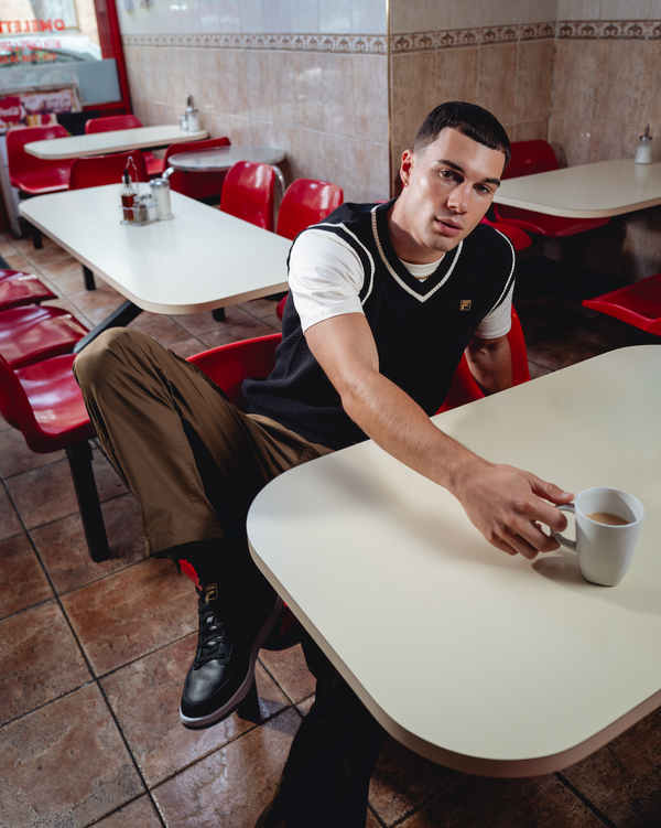 Displays a model wearing the Black 'FILA' branded Mellor Textured Knit Vest with Tipping