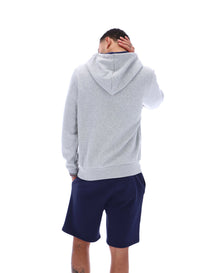 Person wearing a gray hoodie and navy shorts on a white background