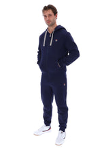 A man modeling a matching navy blue zip-up hoodie and sweatpants tracksuit by Filson, paired with white sneakers, against a solid white background.