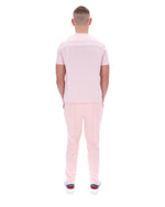 Man wearing a light pink polo shirt and pants on a white background