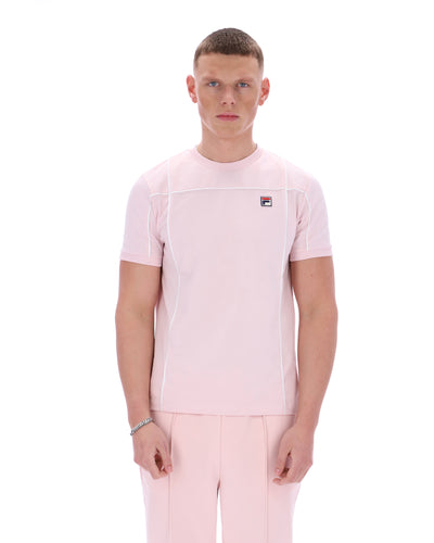 Man wearing a pink t-shirt with a FILA logo on the chest and matching trousers on a white background