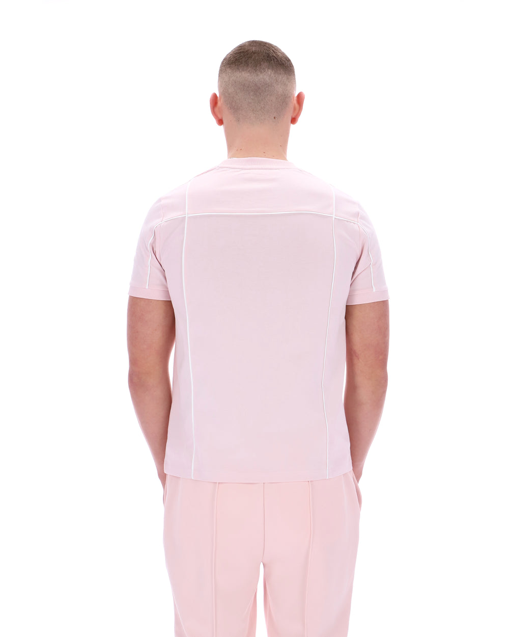 Man wearing a light pink shirt and pants on a white background