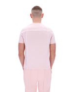 Man wearing a light pink shirt and pants on a white background