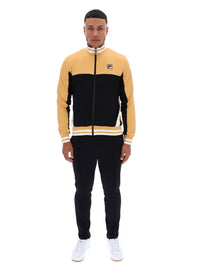 Man wearing a black and beige tracksuit with a FILA logo on the chest, paired with black FILA bottoms, against a white background