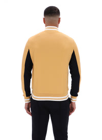 Man wearing a black and beige tracksuit, paired with black FILA bottoms, against a white background