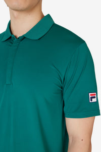 Displays a model wearing the Green 'FILA' branded Tennis Essentials Top featuring the FILA branded logo 