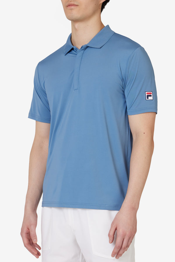 Displays a model wearing the Blue 'FILA' branded Tennis Essentials Top