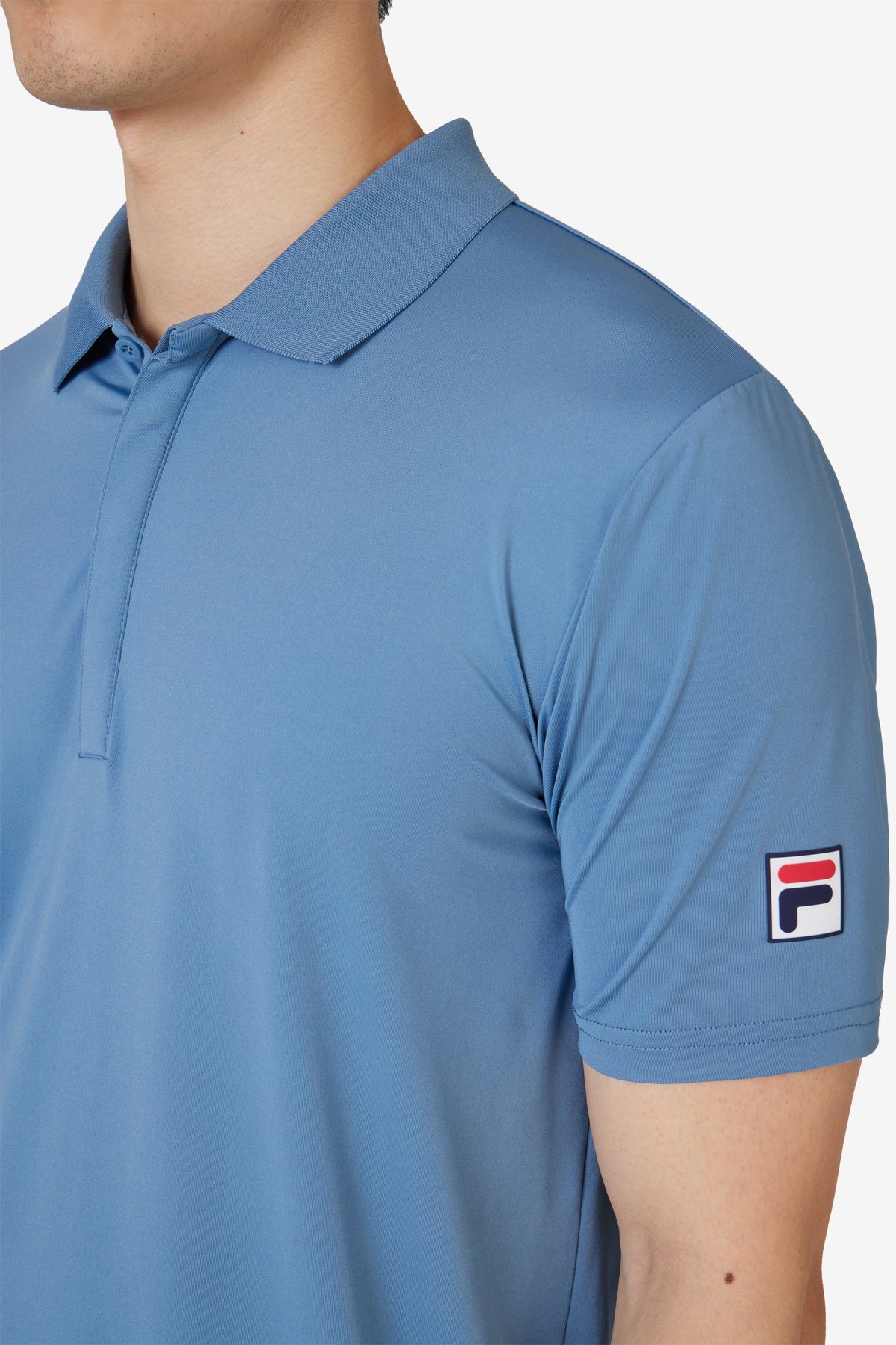 Displays a model wearing the Blue 'FILA' branded Tennis Essentials Top featuring the FILA branded logo 