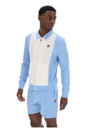 Man wearing a light blue and white tracksuit with a visible brand logo on a white background