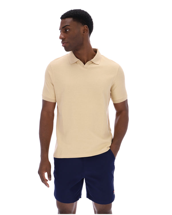 Man wearing a beige polo shirt and navy shorts on a white background